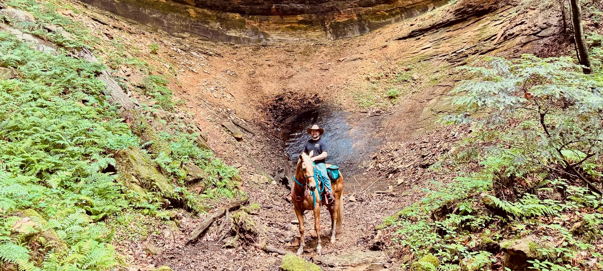 Caleb riding his horse through a rock hollow